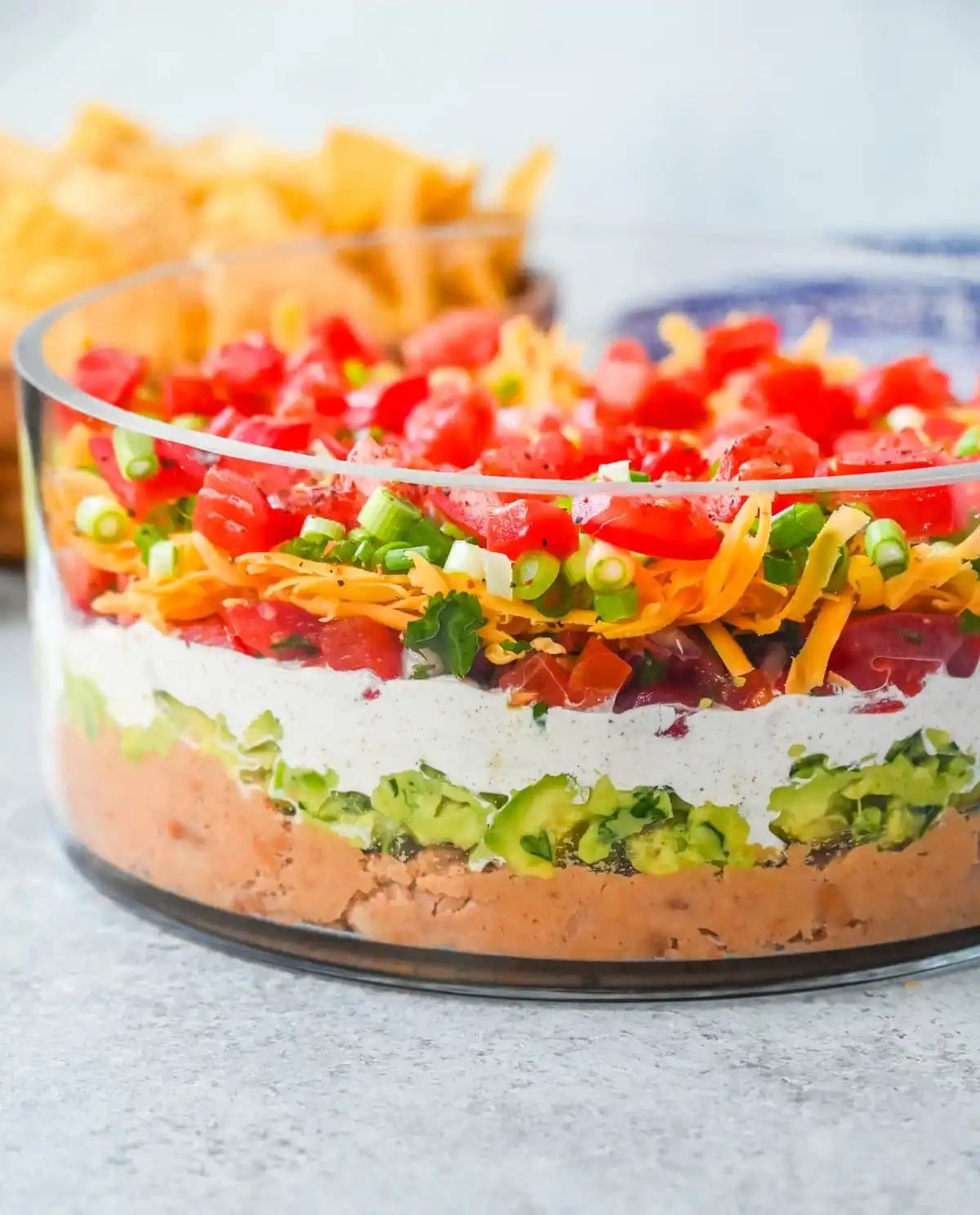 Seven-layer dip is a colorful, Tex-Mex-inspired appetizer featuring layers of refried beans, guacamole, seasoned sour cream, salsa, shredded cheese, fresh tomatoes, and sliced black olives. It’s popular because it’s easy to make, makes a stunning presentation, is delicious, and always a hit at parties or game-day gatherings. Whether you’re hosting a Super Bowl watch party or a casual family get-together, a classic 7 layer dip is guaranteed to impress.