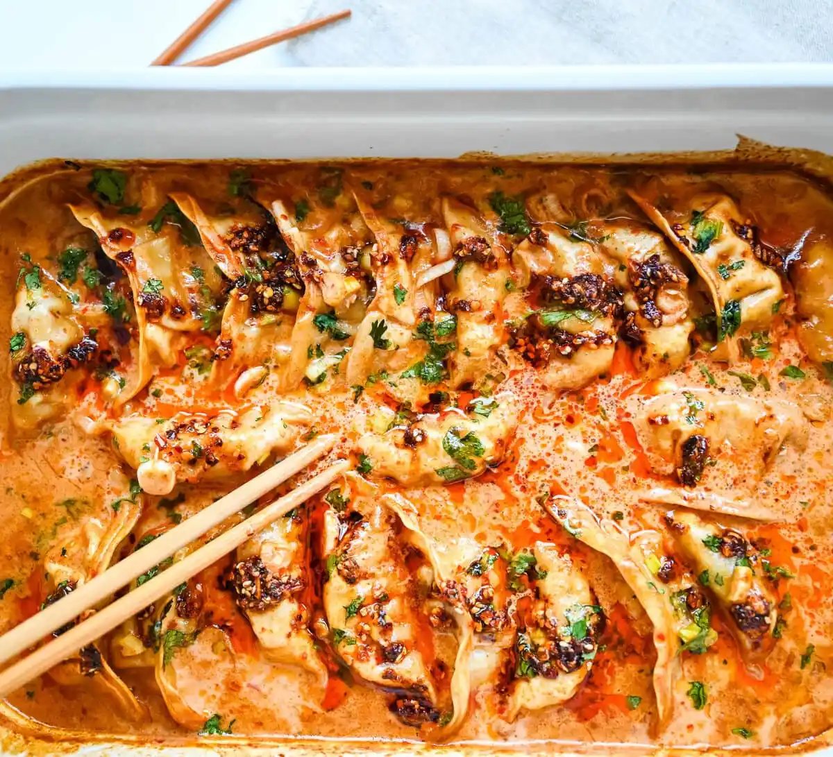 These viral baked dumplings from TikTok are the ultimate easy dinner hack! Crispy dumplings are baked in a creamy coconut curry sauce and topped with cilantro, chili crunch oil, and sesame seeds for the perfect mix of flavor and texture. This is an easy sheet pan dinner recipe!