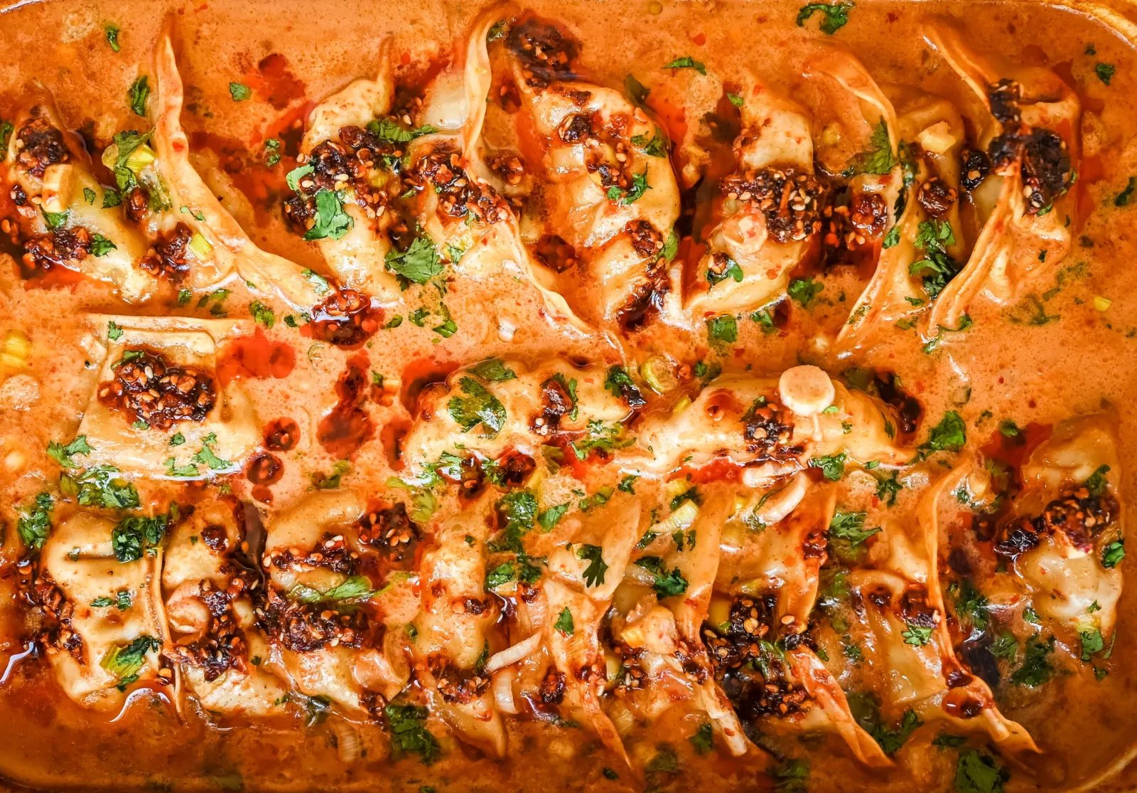 These viral baked dumplings from TikTok are the ultimate easy dinner hack! Crispy dumplings are baked in a creamy coconut curry sauce and topped with cilantro, chili crunch oil, and sesame seeds for the perfect mix of flavor and texture. This is an easy sheet pan dinner recipe!