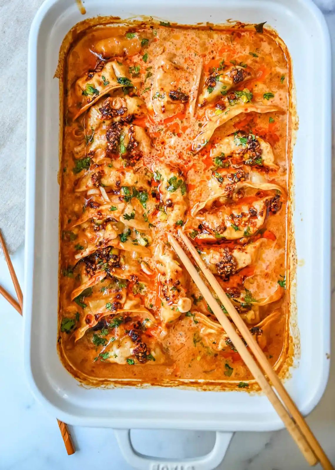 These viral baked dumplings from TikTok are the ultimate easy dinner hack! Crispy dumplings are baked in a creamy coconut curry sauce and topped with cilantro, chili crunch oil, and sesame seeds for the perfect mix of flavor and texture. This is an easy sheet pan dinner recipe!
