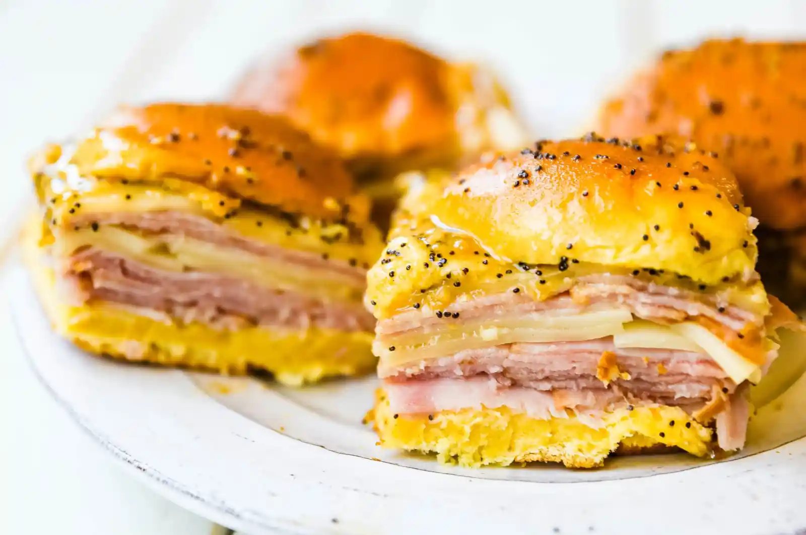 Ham and Cheese Sliders These baked ham and cheese sliders and layered with ham, melted cheese, on a Hawaiian sweet roll, and basted with a flavorful, buttery sauce. www.modernhoney.com #sandwiches #sliders #hamandcheesesliders