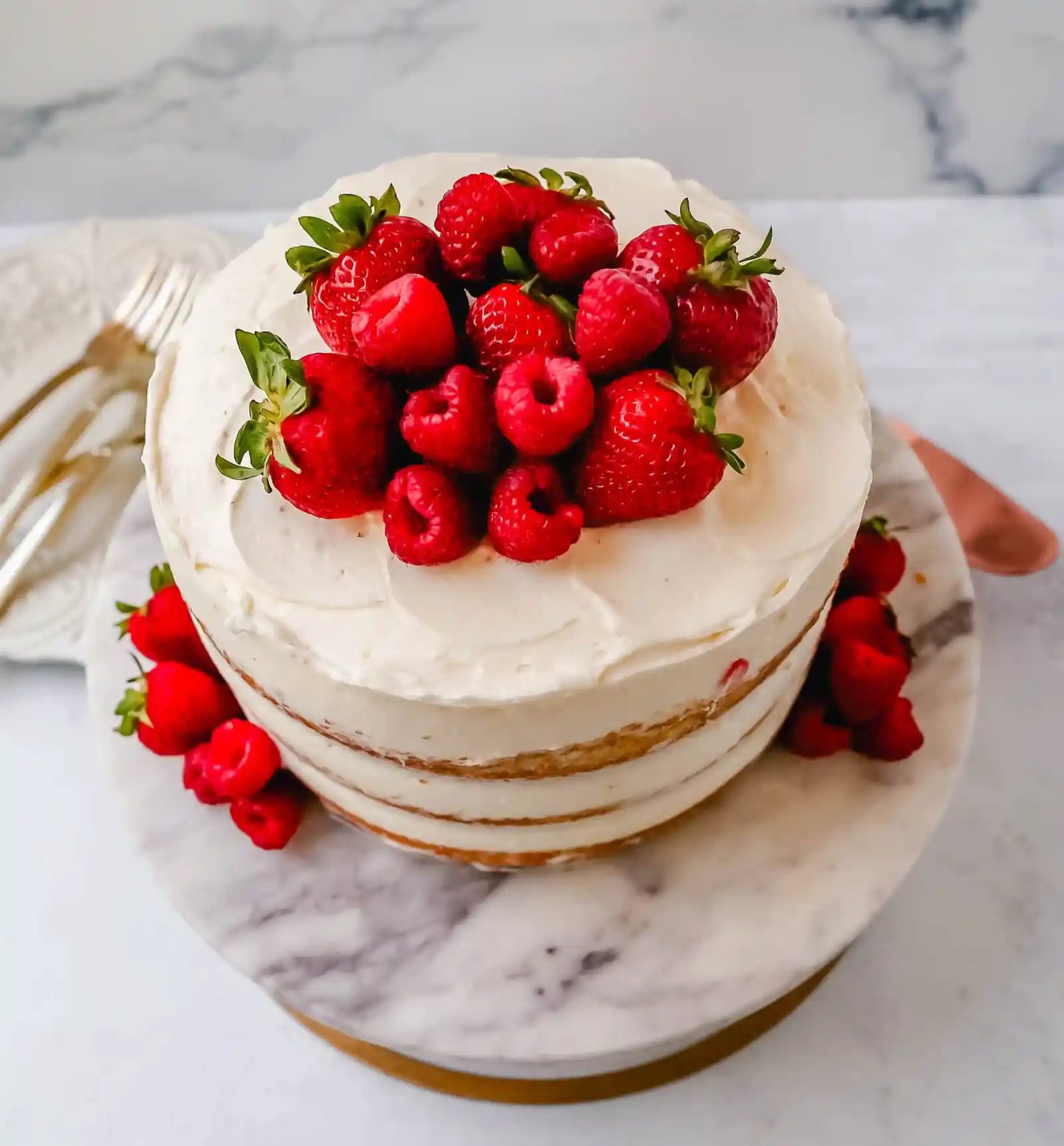 Homemade yellow cake layered with fluffy cream cheese whipped cream frosting and fresh berries.