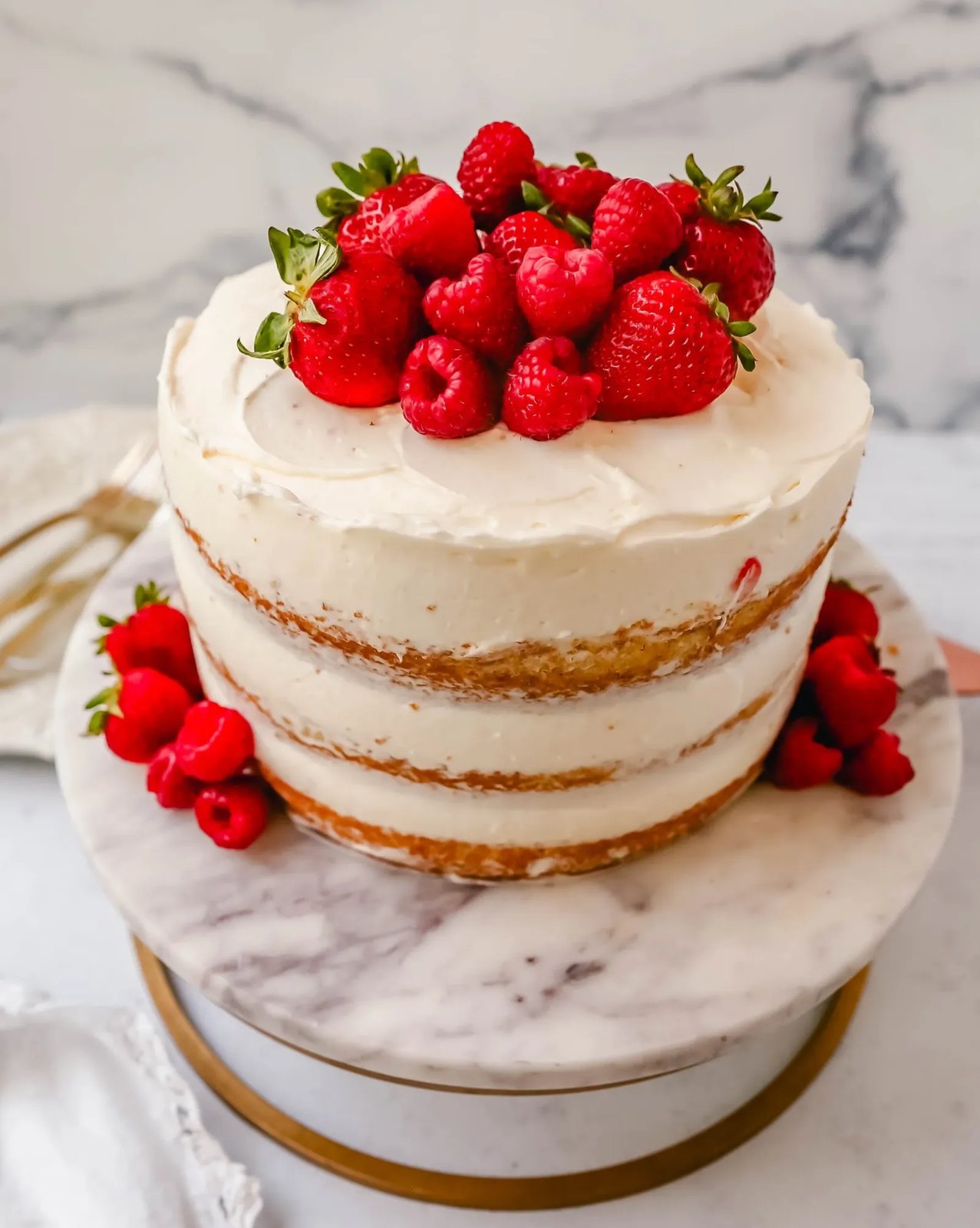 Homemade yellow cake layered with fluffy cream cheese whipped cream frosting and fresh berries.