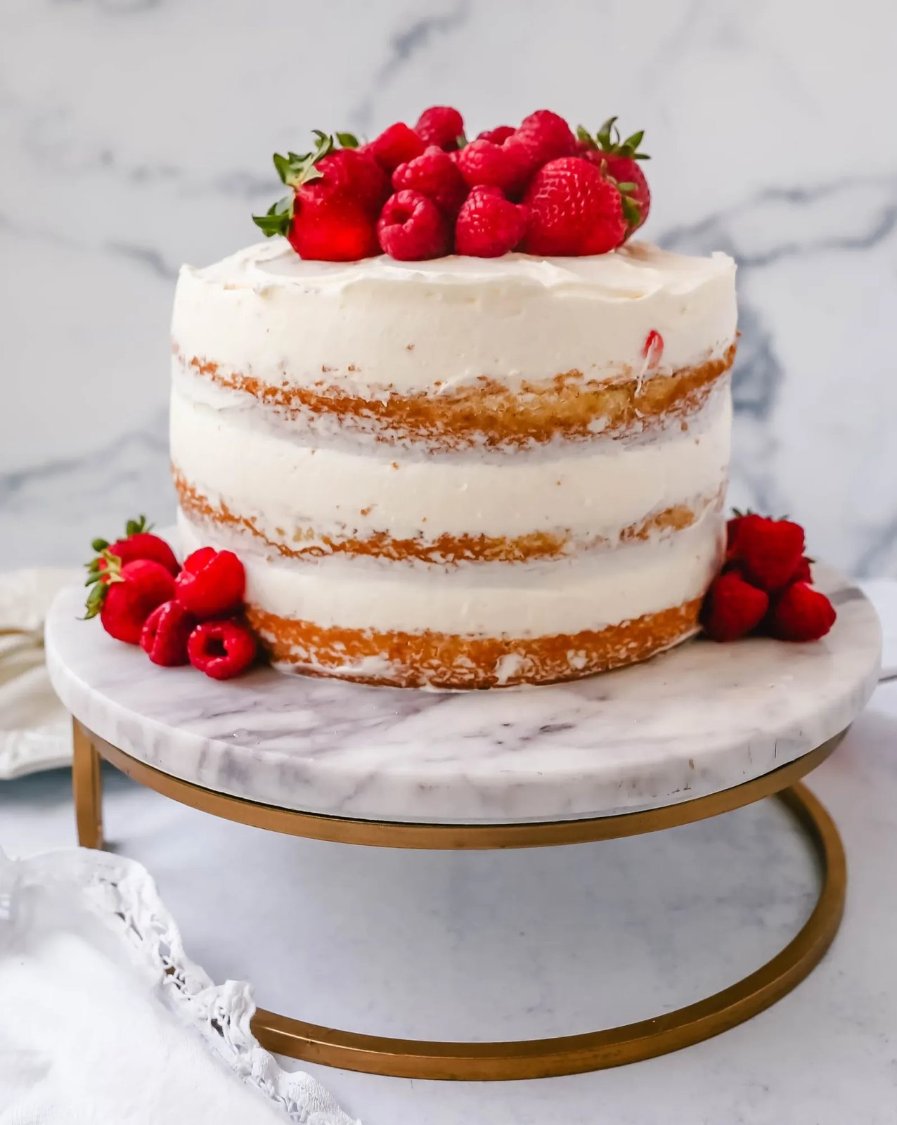Homemade yellow cake layered with fluffy cream cheese whipped cream frosting and fresh berries.