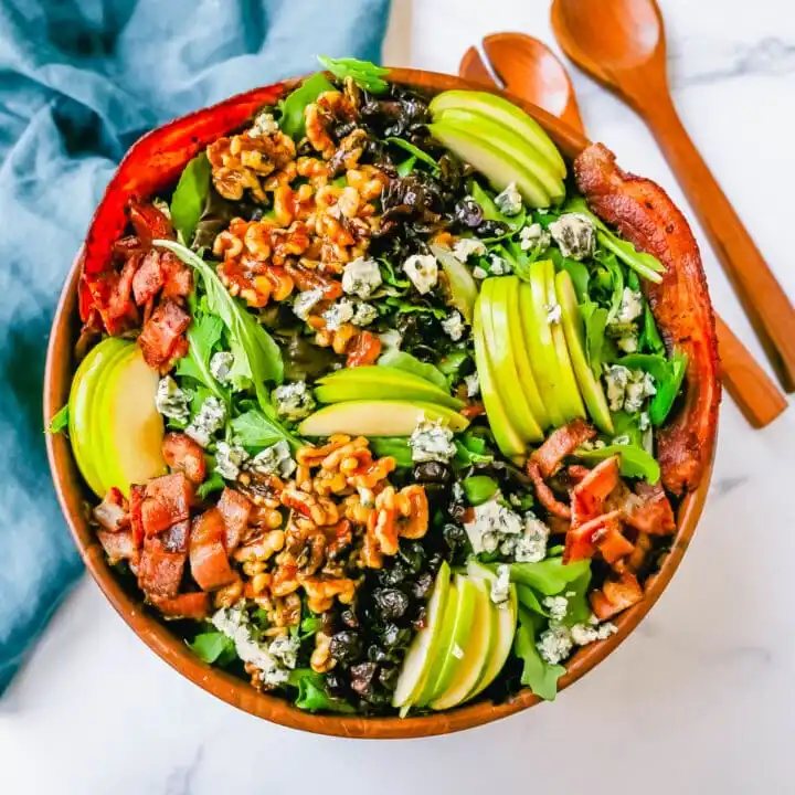 Fall Harvest Salad made with fresh apples, candied walnuts, dried cranberries, feta or blue cheese, crispy bacon all tossed with arugula or spring mix in a homemade apple cider vinegar dressing. The best Fall salad recipe!