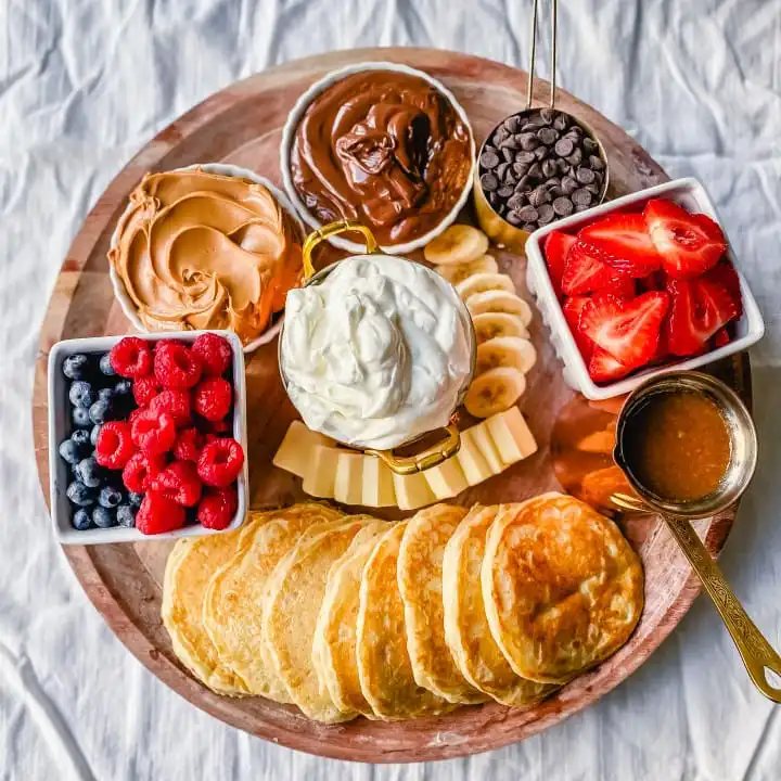 Breakfast Pancake Board. The perfect breakfast for entertaining! Homemade buttermilk pancakes topped with all of your favorite toppings -- fresh berries, whipped cream, homemade syrup, Nutella, chocolate chips, peanut butter, and more.