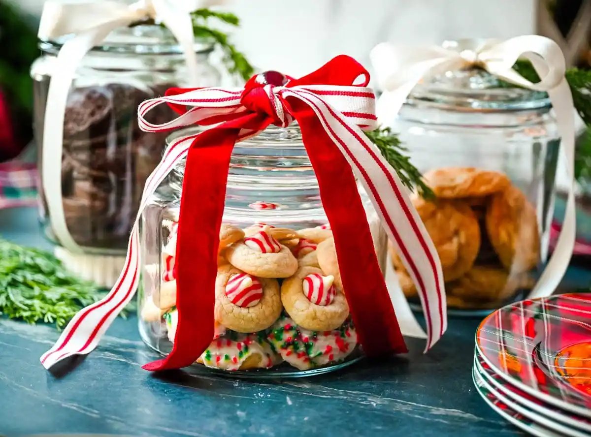 How to make cute glass Christmas cookie jars to give to neighbors, friends, family, and co-workers. It is such a cute way to package cookies. These are Anchor hocking glass jars and perfect for filling with homemade cookies. This is a perfect way to package Christmas cookies.