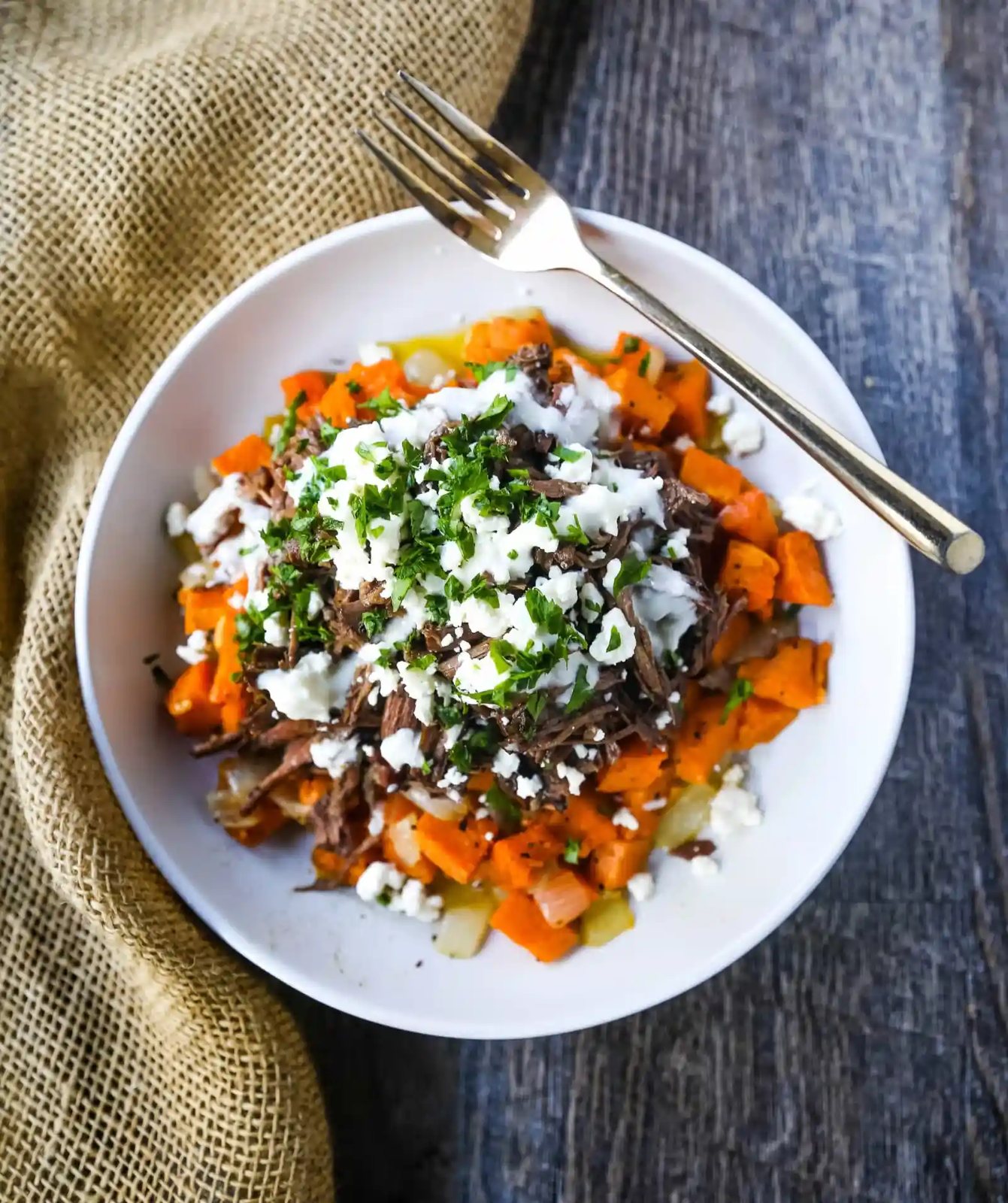 Braised Beef and Sweet Potato Hash Bowl. Tender braised beef on top of a sweet potato onion hash and topped with feta cheese and herbs. www.modernhoney.com #bowl #bowls #dinner
