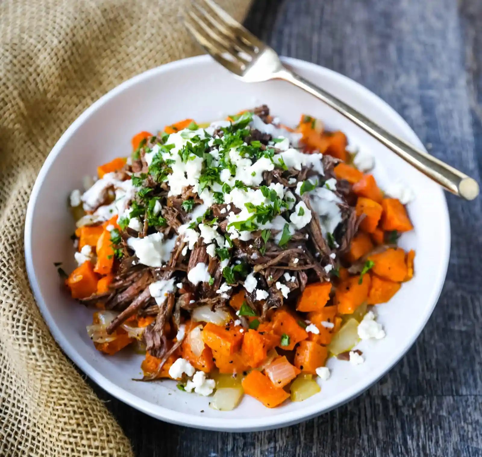 Braised Beef and Sweet Potato Hash Bowl. Tender braised beef on top of a sweet potato onion hash and topped with feta cheese and herbs. www.modernhoney.com #bowl #bowls #dinner