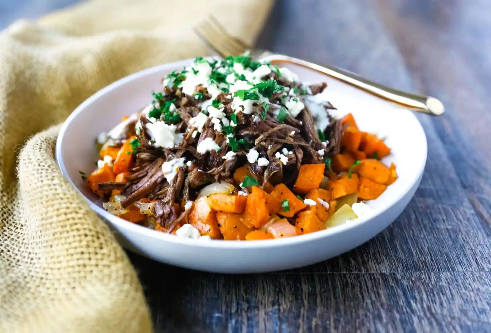Braised Beef and Sweet Potato Hash Bowl. Tender braised beef on top of a sweet potato onion hash and topped with feta cheese and herbs. www.modernhoney.com #bowl #bowls #dinner