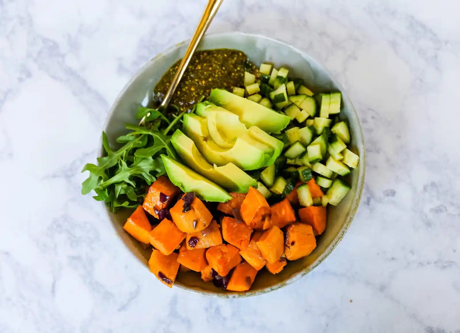 Buddha Bowl with Pistachio Pesto A healthy vegan bowl made with roasted sweet potatoes, onions, fresh avocado, cucumbers, arugula, quinoa, and homemade pistachio pesto. www.modernhoney.com #buddhabowl #vegan #vegetarian #flowerchild