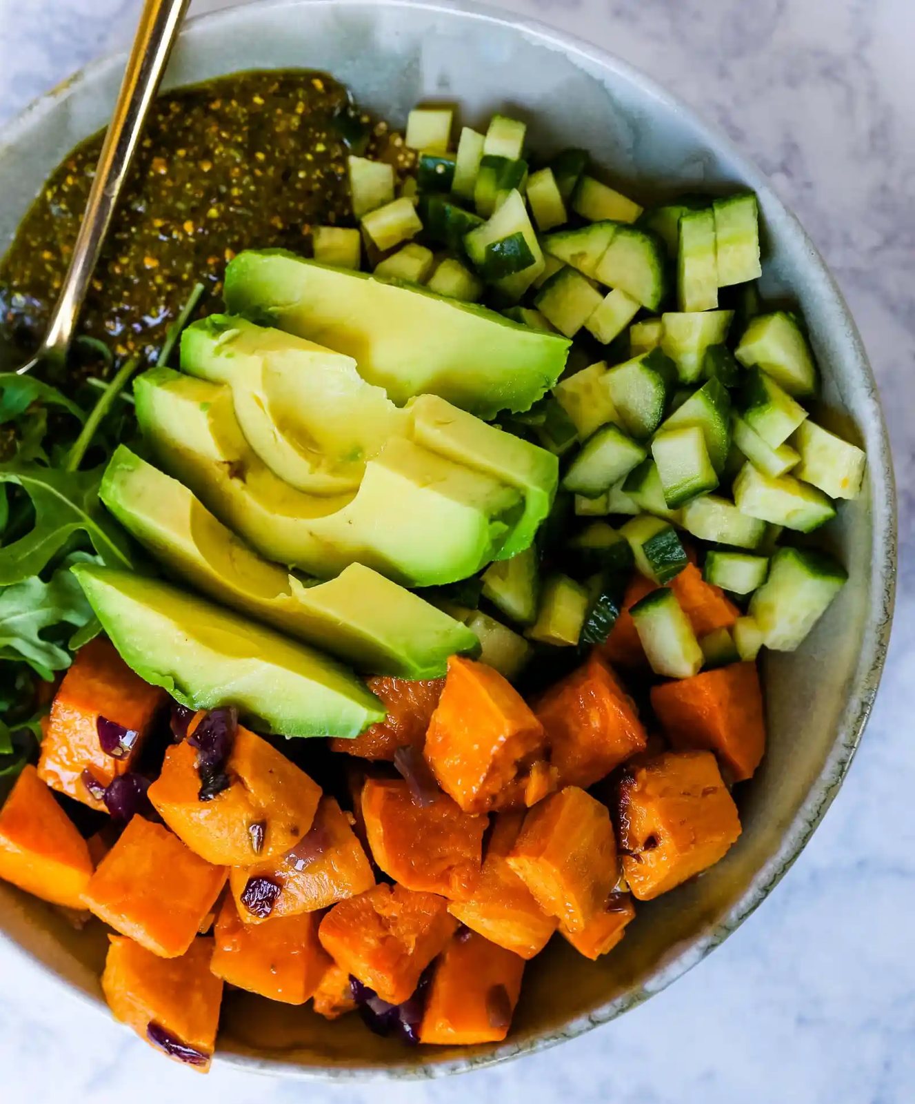 Buddha Bowl with Pistachio Pesto A healthy vegan bowl made with roasted sweet potatoes, onions, fresh avocado, cucumbers, arugula, quinoa, and homemade pistachio pesto. www.modernhoney.com #buddhabowl #vegan #vegetarian #flowerchild