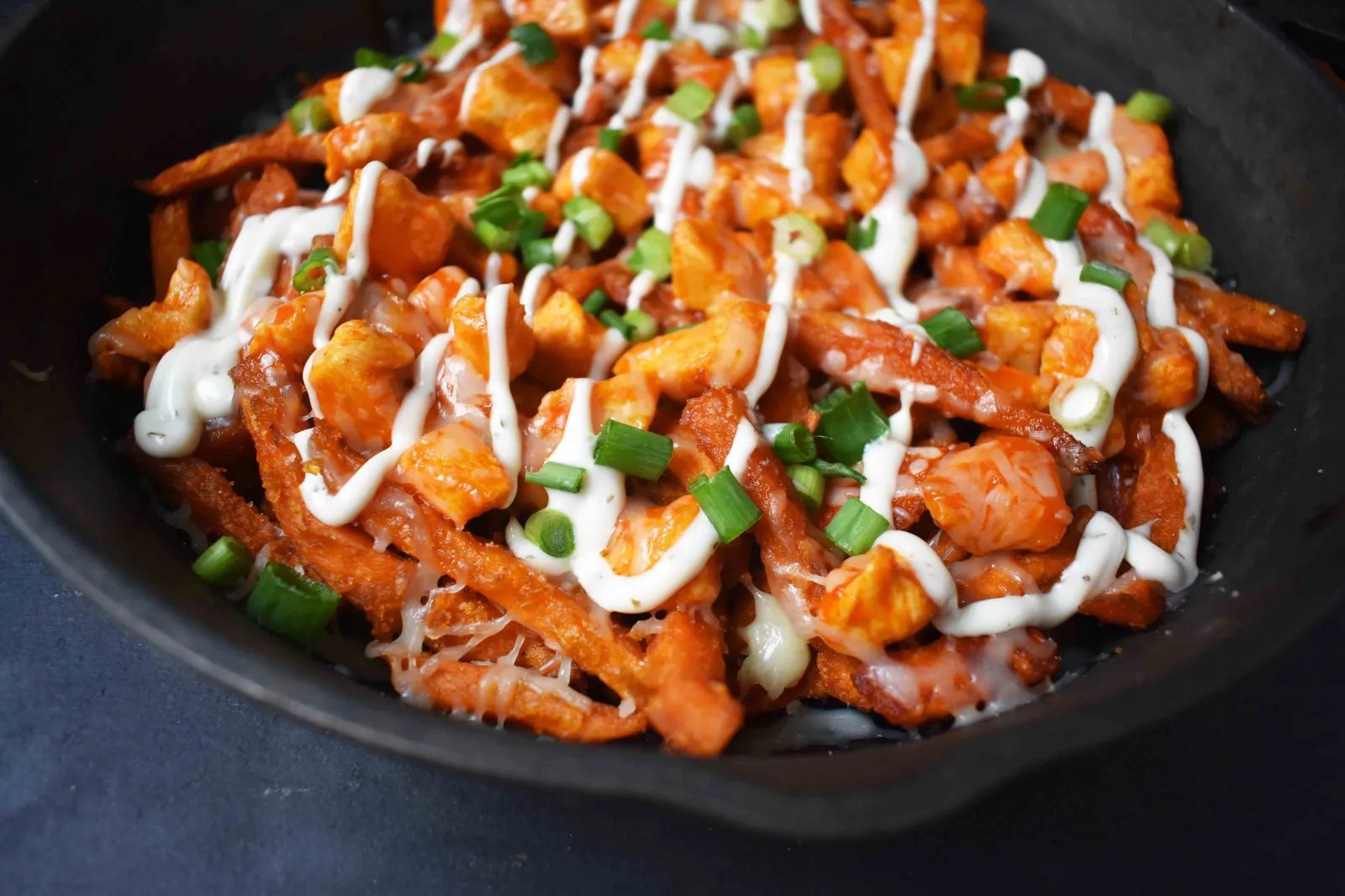 Buffalo Chicken Sweet Potato Fries by Modern Honey. Crisp Sweet Potato Fries topped with Buffalo Wing Chicken, Cheese, Green Onions, and Ranch Dressing.
