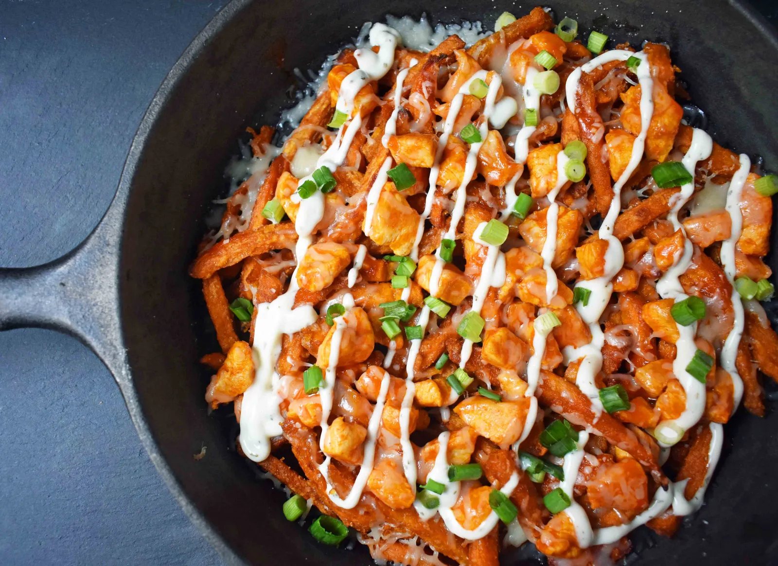 Buffalo Chicken Sweet Potato Fries by Modern Honey. Crisp Sweet Potato Fries topped with Buffalo Wing Chicken, Cheese, Green Onions, and Ranch Dressing.
