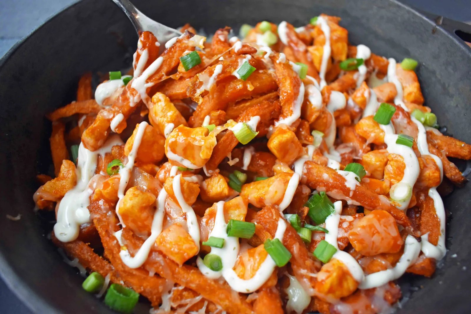 Buffalo Chicken Sweet Potato Fries by Modern Honey. Crisp Sweet Potato Fries topped with Buffalo Wing Chicken, Cheese, Green Onions, and Ranch Dressing.