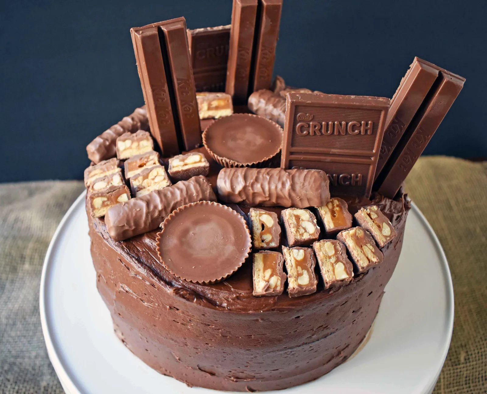 Candy Bar Stash Chocolate Cake by Modern Honey. Perfect chocolate cake topped with chocolate buttercream and the most popular candy bars. It's the ultimate Chocolate Candy Bar Cake.