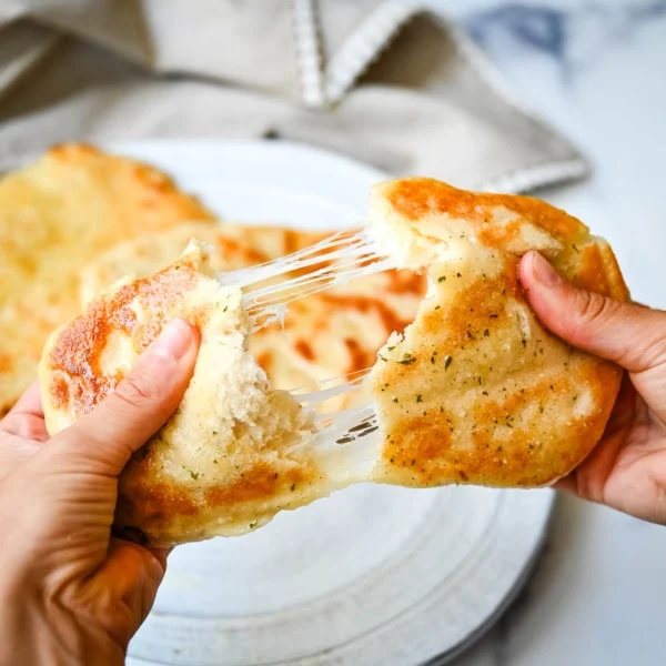 Homemade Cheesy Naan bread stuffed with mozzarella cheese, that is even better than what you find in restaurants. Cheese-stuffed naan is soft, slightly chewy, golden-brown on the outside, fluffy bread layers inside, and melty gooey cheese in the center.