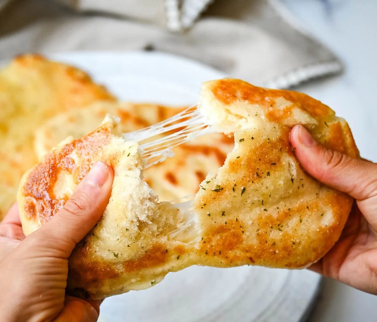 Homemade Cheesy Naan bread stuffed with mozzarella cheese, that is even better than what you find in restaurants. Cheese-stuffed naan is soft, slightly chewy, golden-brown on the outside, fluffy bread layers inside, and melty gooey cheese in the center.