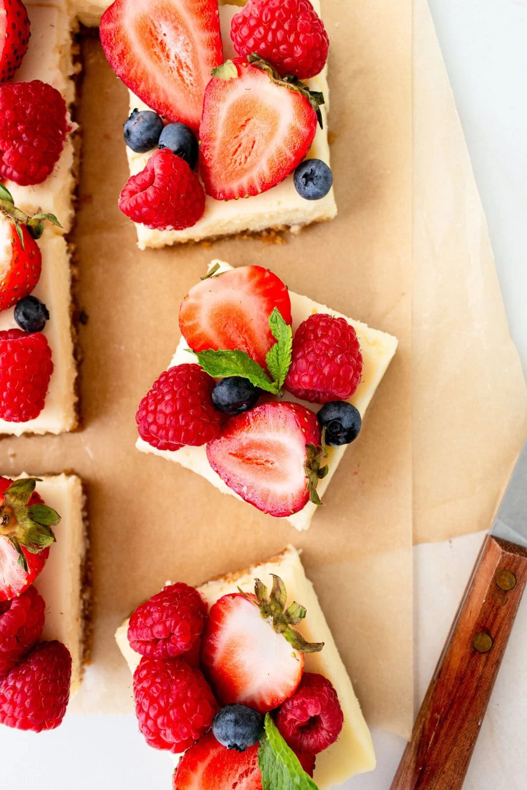Creamy luscious cheesecake bars cut into squares with a buttery graham cracker crust and topped with fresh berries is a crowd-pleasing popular dessert! They feature a creamy, tangy cheesecake filling atop a buttery graham cracker crust, baked to perfection in a bar form. Whether you're looking for a treat for a party, a family dessert, or simply craving cheesecake, these cheesecake bars are a hit.