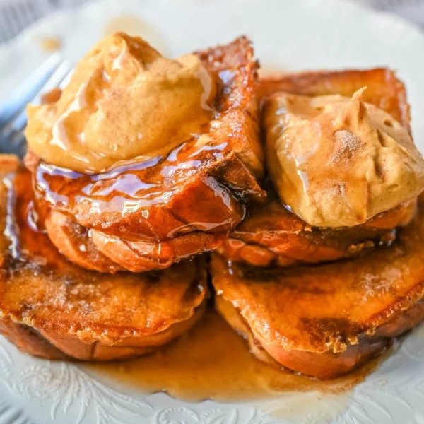 This Pumpkin French Toast is the perfect fall breakfast! Made with pumpkin puree, pumpkin spice, and thick slices of brioche cinnamon bread, it’s golden on the outside, soft inside, and topped with a dollop of sweet brown sugar pumpkin spice cream cheese.