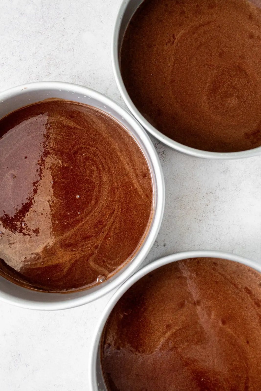 Homemade chocolate cake batter in cake pans ready to bake.