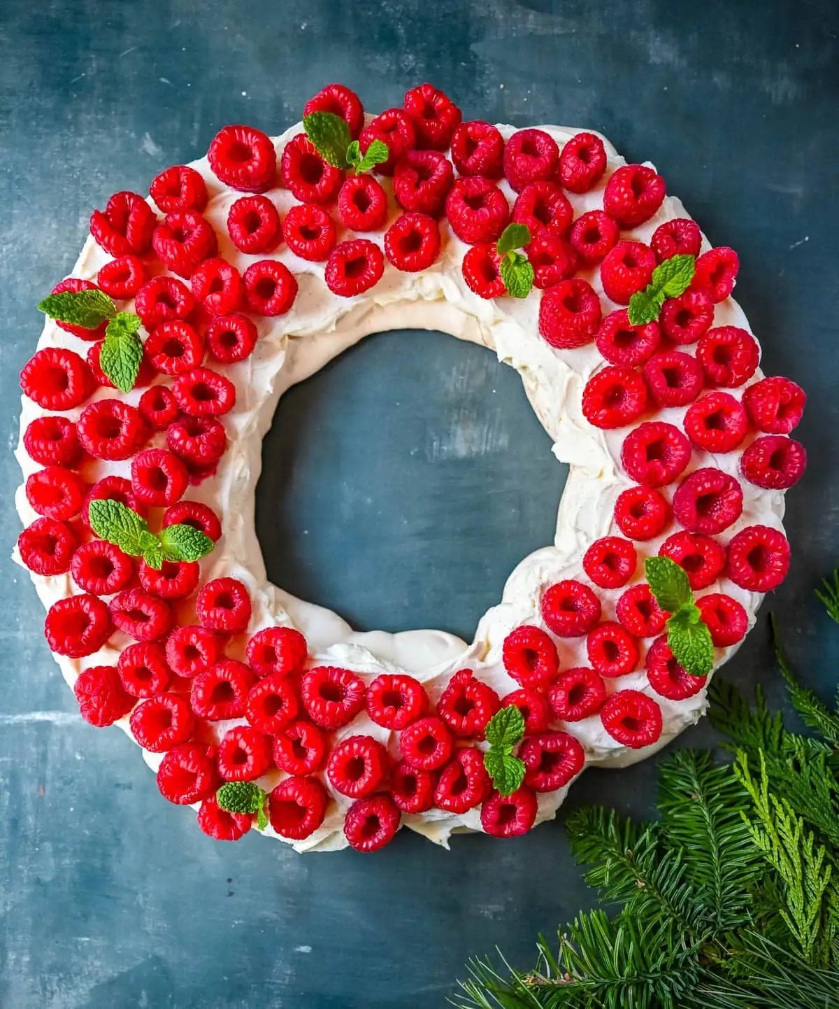 This Christmas Pavlova is a show-stopping holiday dessert with a crisp meringue shell, marshmallow-soft center, and dreamy mascarpone whipped cream piled high with fresh raspberries. A gorgeous Christmas dessert that feels fancy but is actually foolproof.