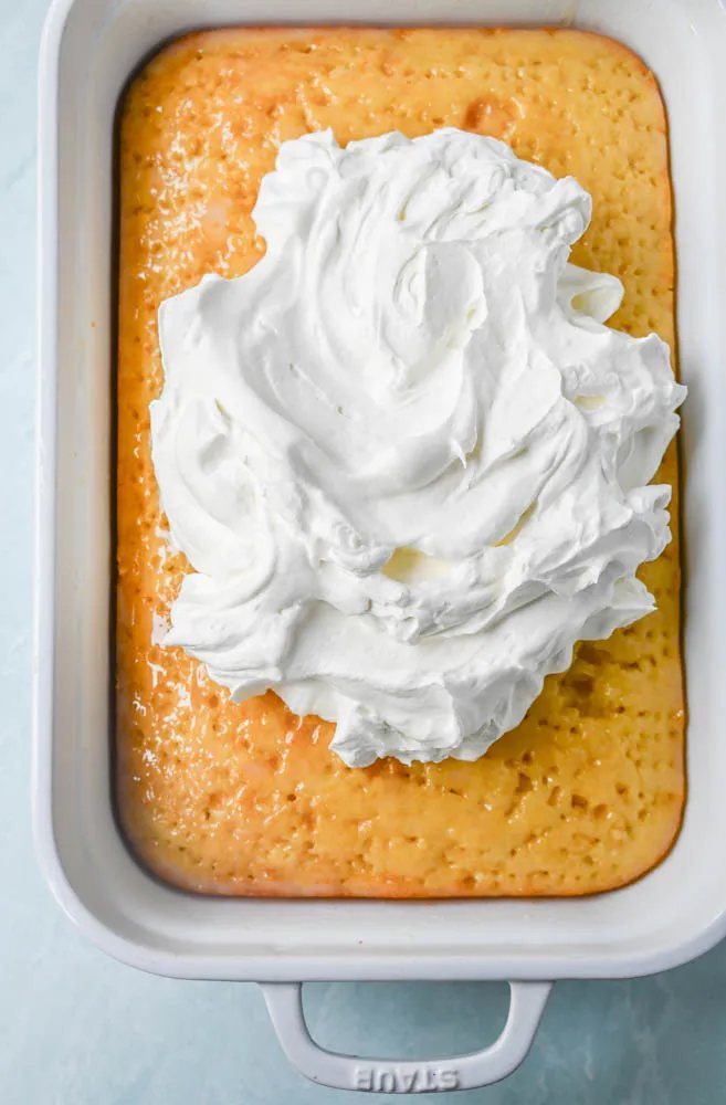 This Coconut Poke Cake is made with a baked cake mix and filled with cream of coconut and sweetened condensed milk and topped with sweet whipped cream and coconut. This Coconut Tres Leches Cake is so easy to make and is perfect for potlucks and parties.