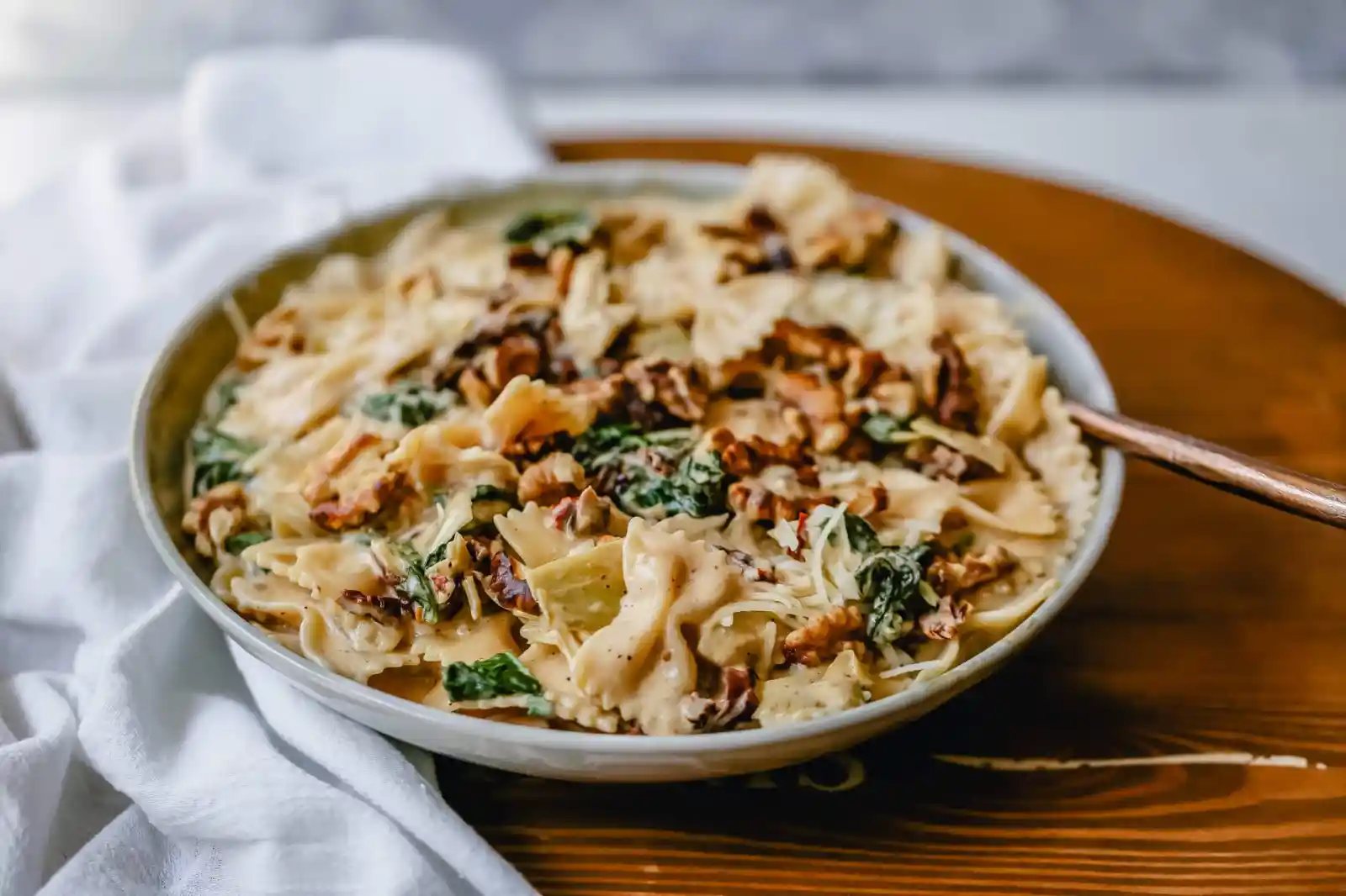 Creamy Bowtie Pasta with Sundried Tomatoes Bowtie Pasta tossed with a garlic sundried tomato cream sauce with artichoke hearts and parmesan cheese and crunchy toasted walnuts. A quick 20-minute weeknight meal. #pasta #dinner