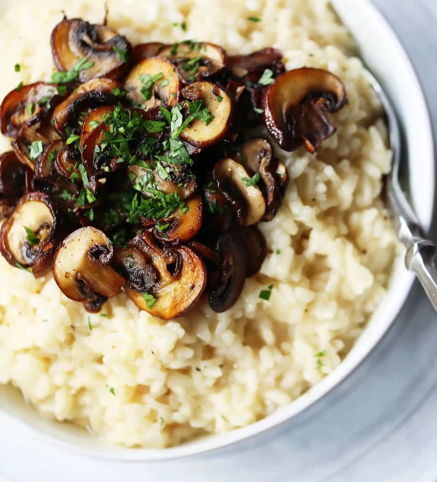 Creamy Mushroom Risotto. Rich, creamy rice slowly simmered with chicken broth, butter, parmesan cheese, and topped with butter sauteed mushrooms. www.modernhoney.com #risotto #homemaderisotto #mushroomrisotto