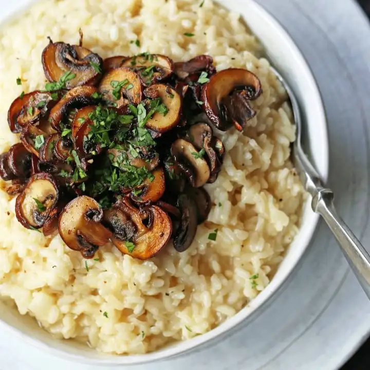 Creamy Mushroom Risotto. Rich, creamy rice slowly simmered with chicken broth, butter, parmesan cheese, and topped with butter sauteed mushrooms. www.modernhoney.com #risotto #homemaderisotto #mushroomrisotto
