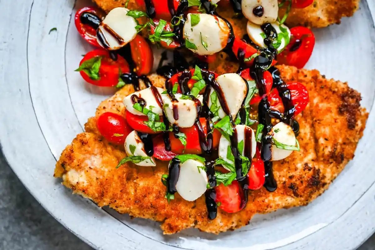 Crispy Caprese Chicken is crispy panko-crusted chicken topped with a fresh grape tomato and mozzarella caprese salad, finished with balsamic glaze. A simple, restaurant-worthy dinner ready in 30 minutes.