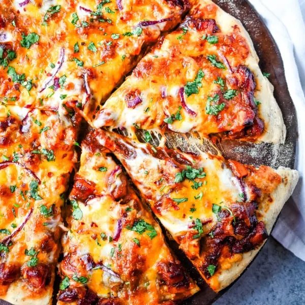 This Homemade BBQ Chicken Pizza is made with a Homemade Pizza Crust, BBQ Ranch Sauce, Mozzarella and Cheddar Cheeses, Red Onion, and a touch of Cilantro. THE BEST BBQ CHICKEN PIZZA RECIPE.