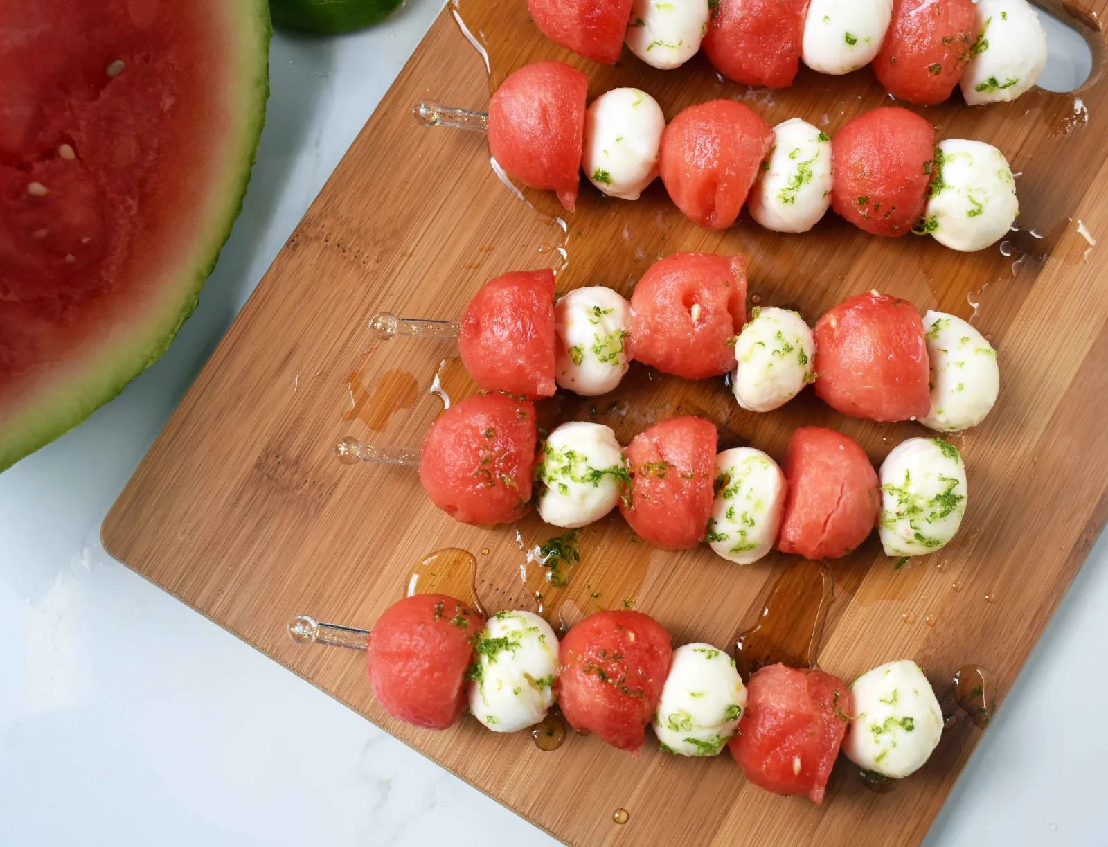 Fresh Mozzarella Watermelon Skewers with Honey Lime Drizzle. Round watermelon and fresh mozzarella balls and layered to make a kabob and drizzled with homemade honey lime sauce. A perfect appetizer or side dish for any BBQ or party. www.modernhoney.com