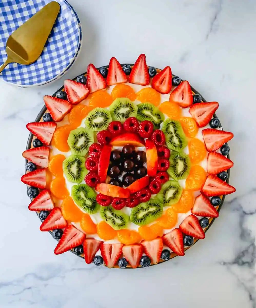 Fruit Pizza with a Sugar Cookie Crust is made with a large, pizza-sized baked sugar cookie and topped with a sweet cream cheese whipped cream and sprinkled with glazed fresh fruit.