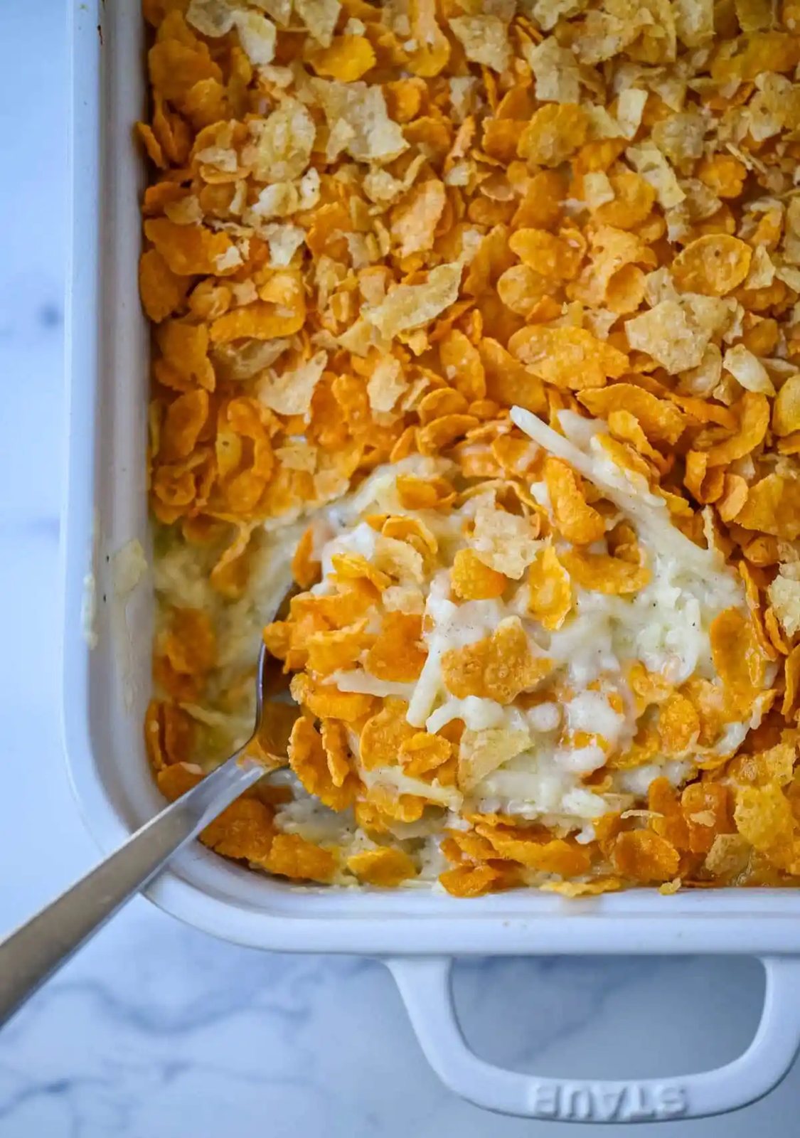This creamy, cheesy funeral potatoes recipe is the ultimate comfort food casserole made with hash browns, sour cream, cheddar, and a rich homemade sauce. Topped with a crispy cornflake and potato chip crust, it’s perfect for Easter, potlucks, and family dinners. Learn how to make the best funeral potatoes from scratch -- no canned soup needed.