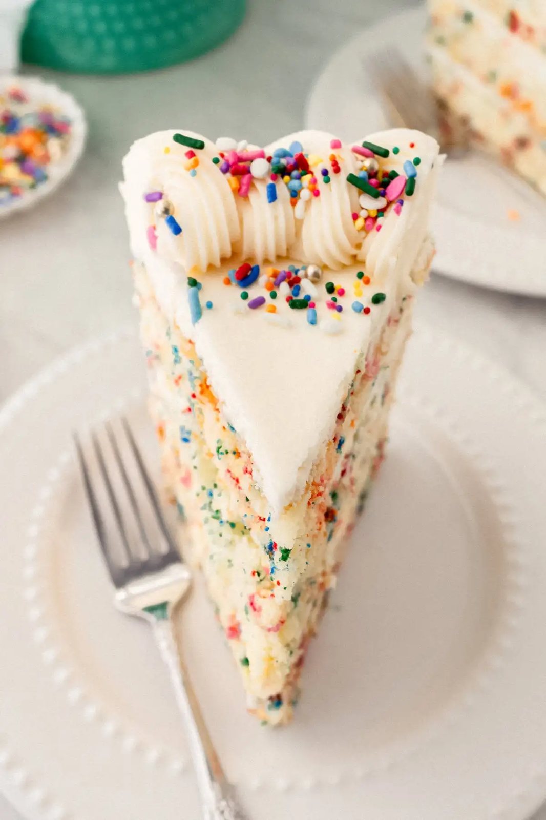 A fluffy homemade Funfetti birthday cake with rainbow sprinkles topped with a light cream cheese buttercream frosting and an array of sprinkles. This Confetti Cake recipe is the perfect birthday cake!