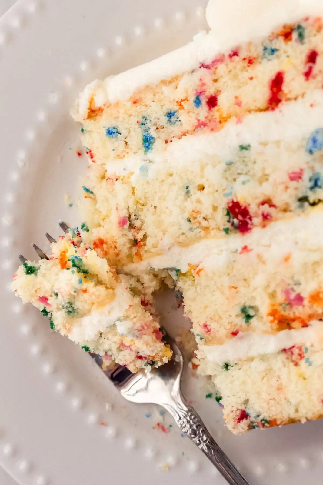 A fluffy homemade Funfetti birthday cake with rainbow sprinkles topped with a light cream cheese buttercream frosting and an array of sprinkles. This Confetti Cake recipe is the perfect birthday cake!