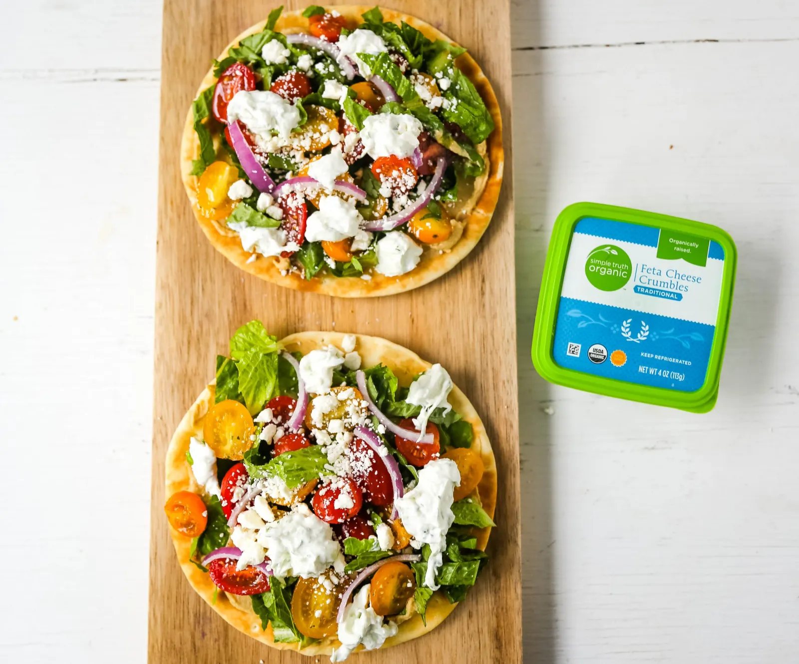 Greek Salad Pita Pizzas Soft pita bread topped with creamy hummus, romaine lettuce, juicy grape tomatoes, feta cheese, red onion, cucumber, and a homemade fresh tzatziki sauce. www.modernhoney.com #greek #greekfood #salad #pita