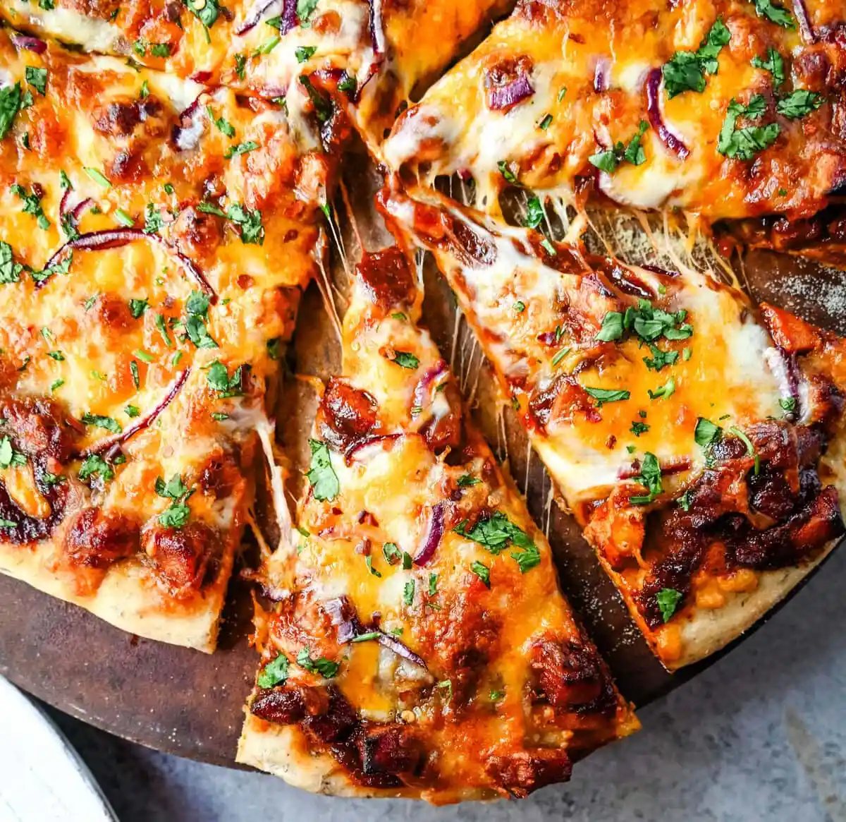 This Homemade BBQ Chicken Pizza is made with a Homemade Pizza Crust, BBQ Ranch Sauce, Mozzarella and Cheddar Cheeses, Red Onion, and a touch of Cilantro. THE BEST BBQ CHICKEN PIZZA RECIPE.