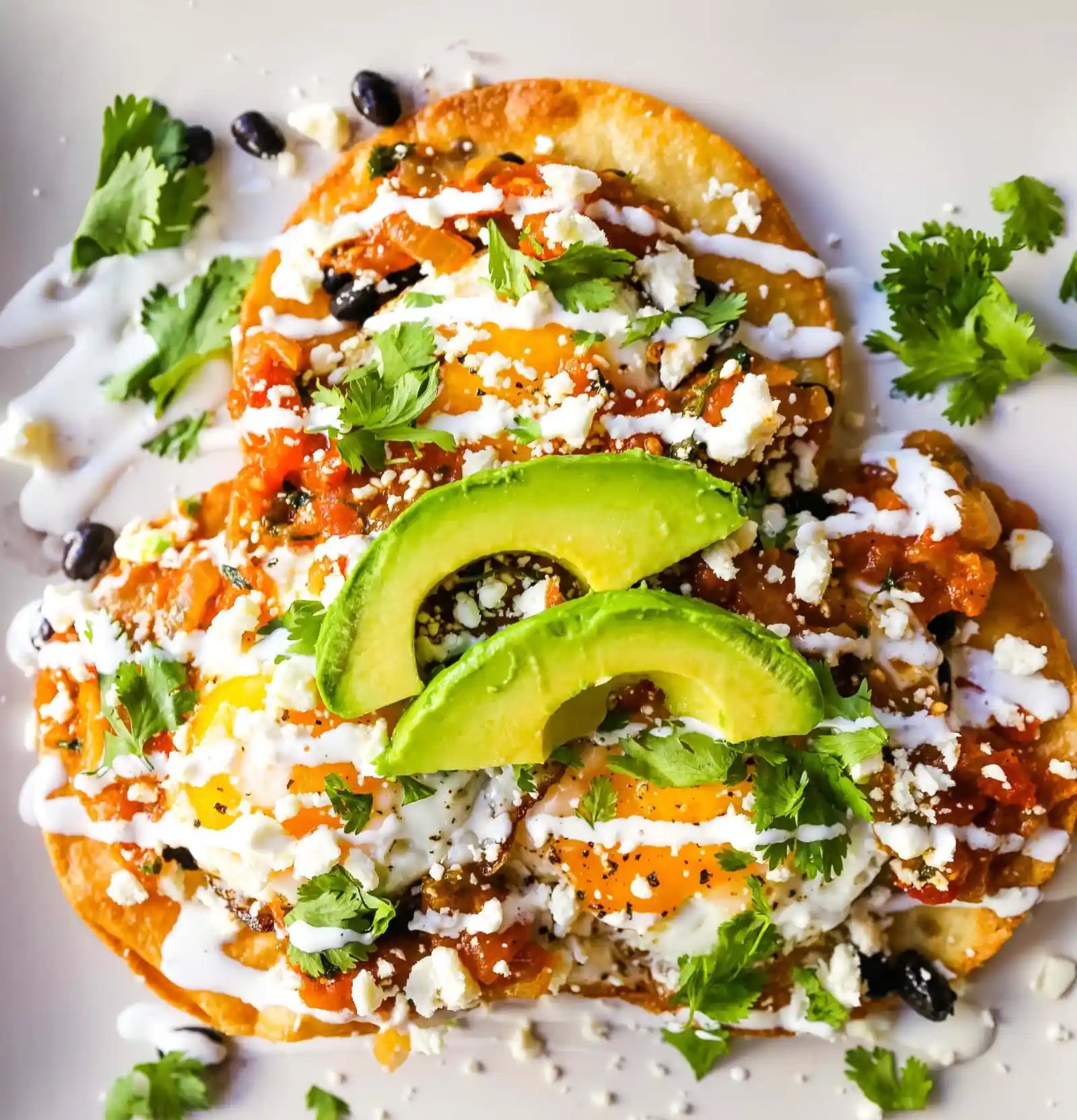 Huevos Rancheros. A traditional Mexican breakfast dish made with fried corn tortillas, fried egg, ranchera salsa, beans, avocado, cheese, and salsa. #huevosrancheros #mexican #mexicanfood #breakfast