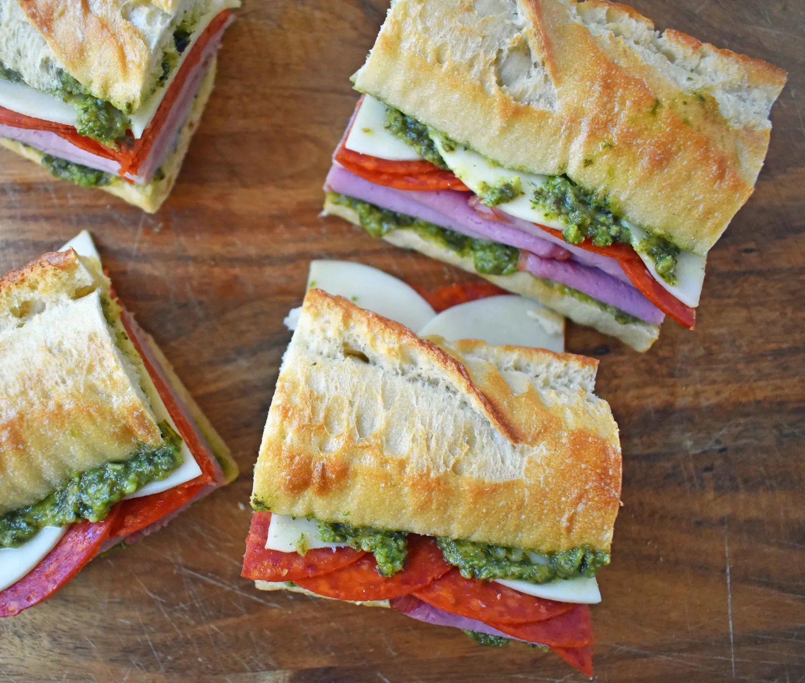 Italian Pressed Sandwiches made with rustic French bread layered with Italian meats and cheeses, pesto sauce or olive oil and vinegar, and marinated tomatoes. This Italian Pressed Sandwich with pesto sauce is perfect for a picnic, kids lunch, or for a casual lunch. www.modernhoney.com