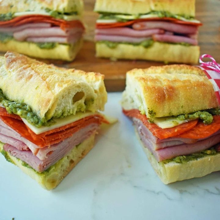 Italian Pressed Sandwiches made with rustic French bread layered with Italian meats and cheeses, pesto sauce or olive oil and vinegar, and marinated tomatoes. This Italian Pressed Sandwich with pesto sauce is perfect for a picnic, kids lunch, or for a casual lunch. www.modernhoney.com