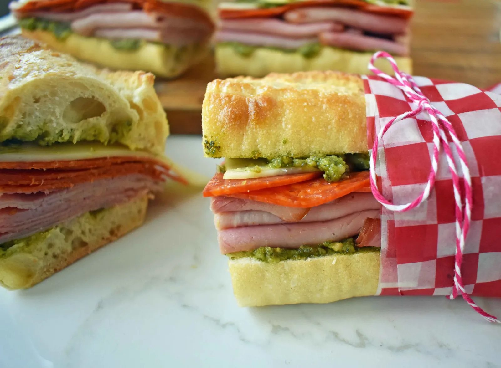 Italian Pressed Sandwiches made with rustic French bread layered with Italian meats and cheeses, pesto sauce or olive oil and vinegar, and marinated tomatoes. This Italian Pressed Sandwich with pesto sauce is perfect for a picnic, kids lunch, or for a casual lunch. www.modernhoney.com