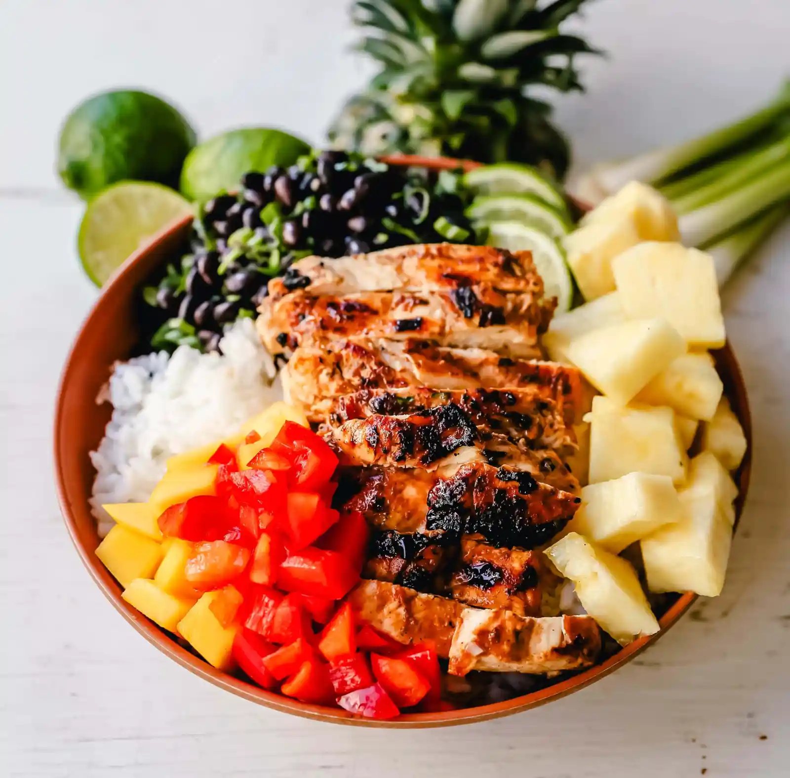 Jerk Chicken Bowl Jamaican spiced grilled Jerk Chicken with rice, black beans, cilantro, fresh pineapple and mango, and red peppers. www.modernhoney.com #jerkchicken #chicken #chickenbowl