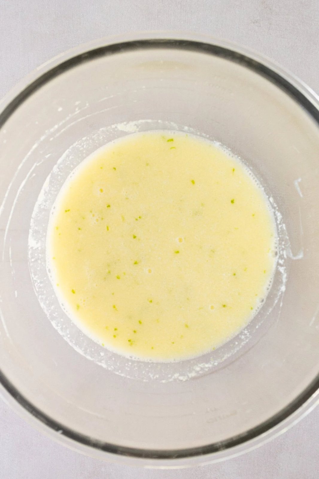 Making a homemade key lime cake batter with fresh ingredients.