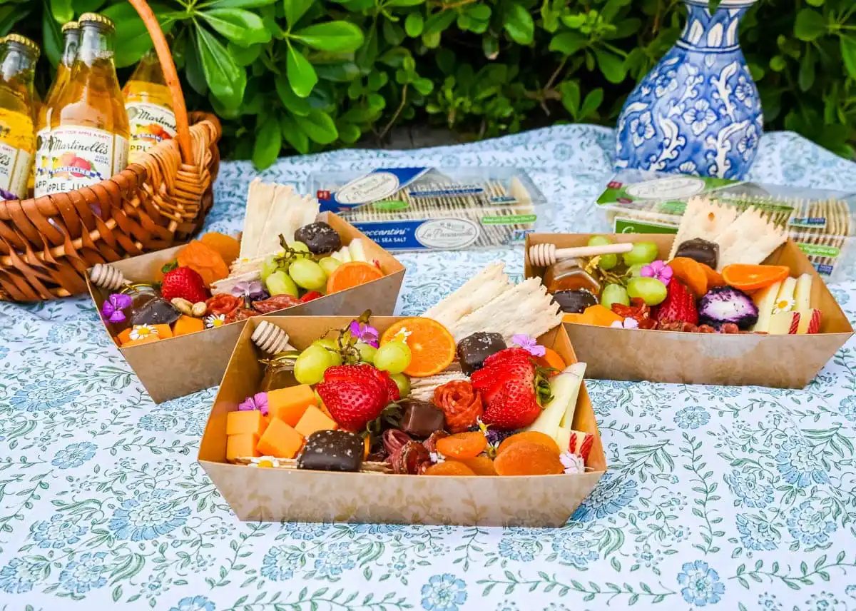 Mini Charcuterie Box on picnic. Charcuterie boards have become the epitome of gourmet snacking. But what if you are craving a charcuterie board but you want it on a smaller scale? Enter the mini charcuterie box – a perfect personal-sized grazing box that packs all the flavor in a small package.