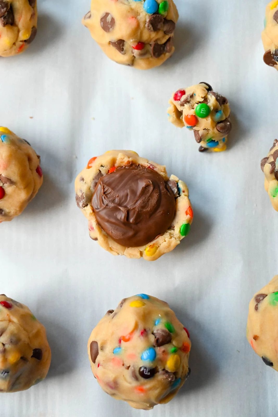 M&M Nutella Lava Cookie stuffed with Nutella. Freeze dollops of nutella before placing in the center of a cookie dough ball and wrap cookie dough around it.