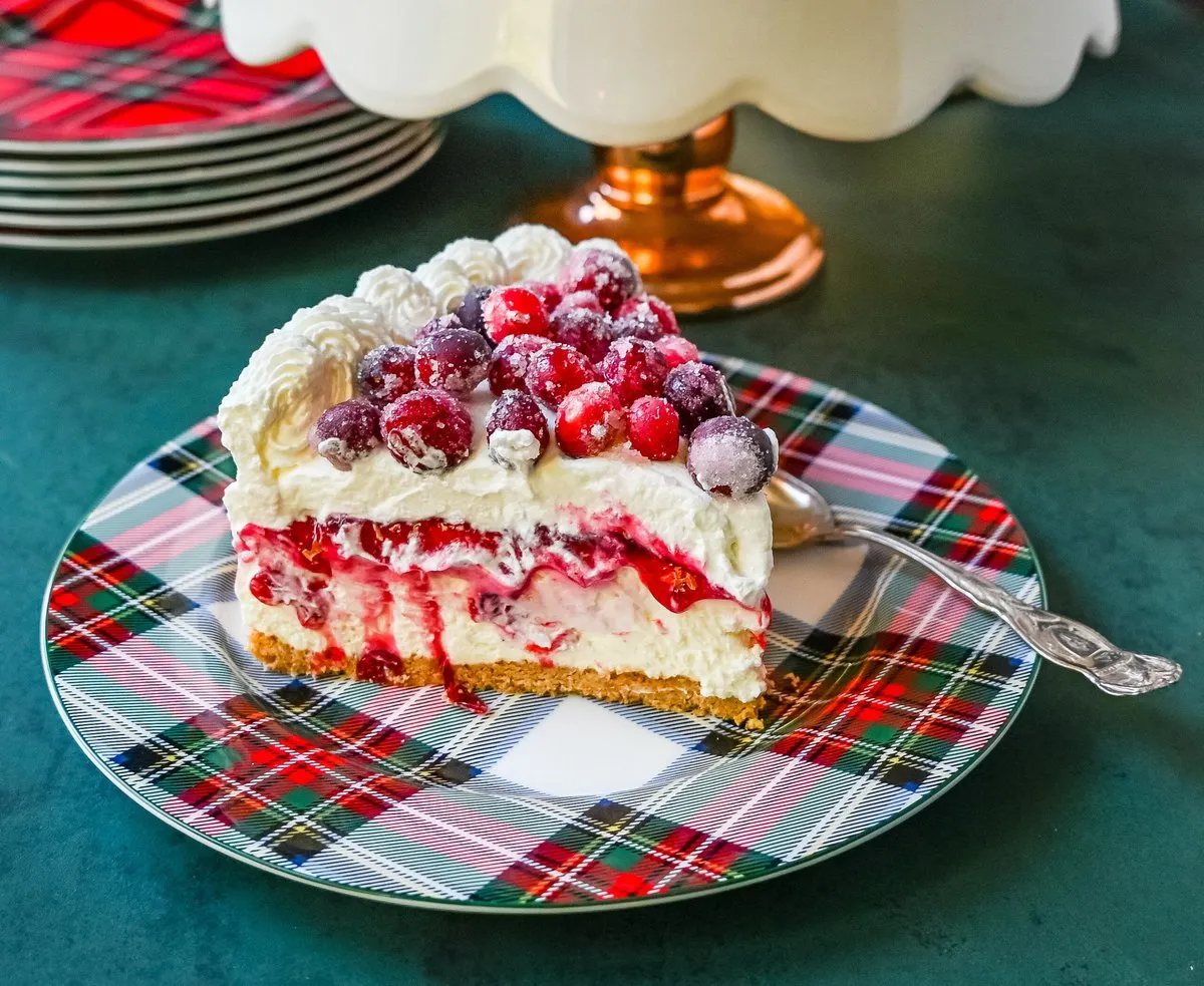 No-Bake Cranberry White Chocolate Cheesecake. This is a beautiful Christmas Cranberry Cheesecake perfect for the holidays. This no-bake white chocolate cheesecake has a graham cracker crust, white chocolate cream cheese filling, topped with homemade cranberry jam, sugared cranberries, and whipped cream.