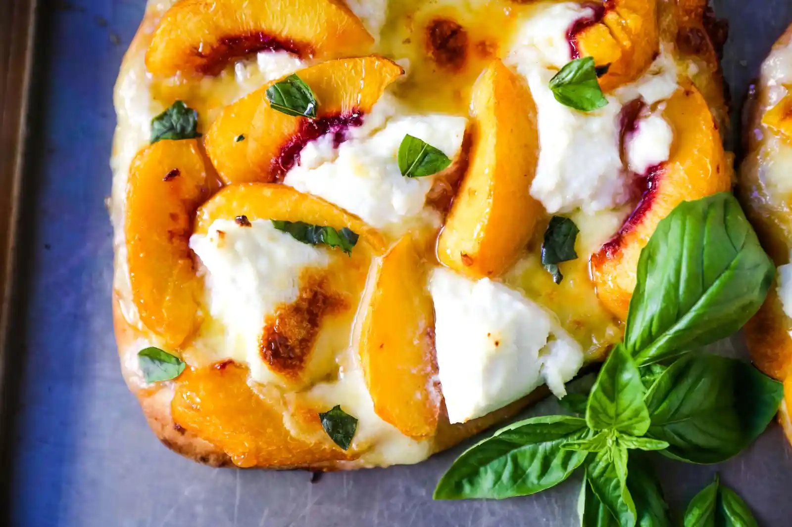 Peach Basil Mozzarella Flatbread Fresh peaches, basil ribbons, ricotta cheese, a drizzle of honey, fresh mozzarella all on a buttery flatbread. The perfect summer pizza! www.modernhoney.com #peachpizza #flatbread #peachflatbread #summerpizza #peachrecipes