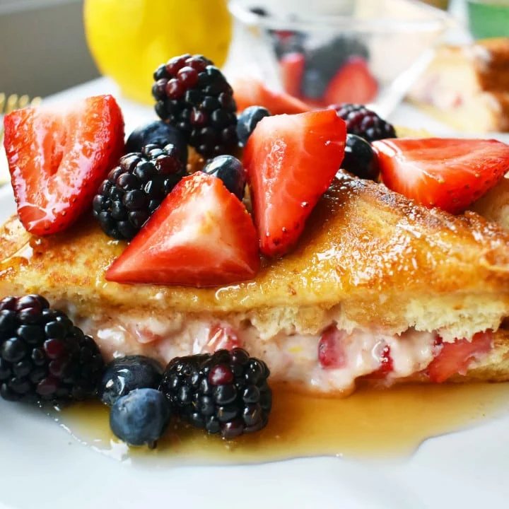 Strawberries and Cream French Toast. Sweet cream cheese, jam and fresh strawberries stuffed between two pieces of soft Texas toast. Dipped into a rich custard batter and cooked until golden brown in skillet. Gourmet french toast made in less than 15 minutes. Perfect topped with fresh berries and homemade whipped cream. www.modernhoney.com